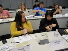 Megan sees how Melissa is taping her bacteria plate.