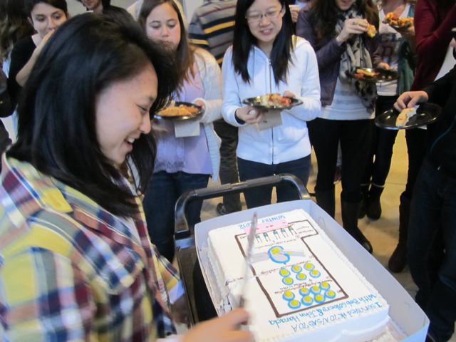 Elaine slices cake right down the middle.